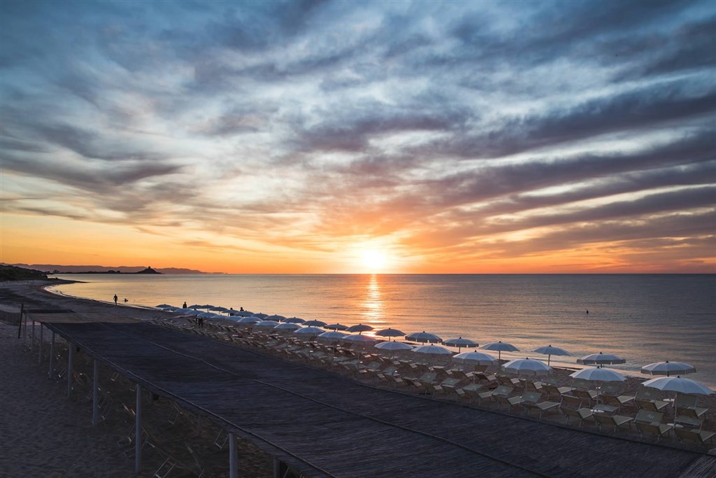 Západ slunce a hotelová pláž, Pula, Sardinie