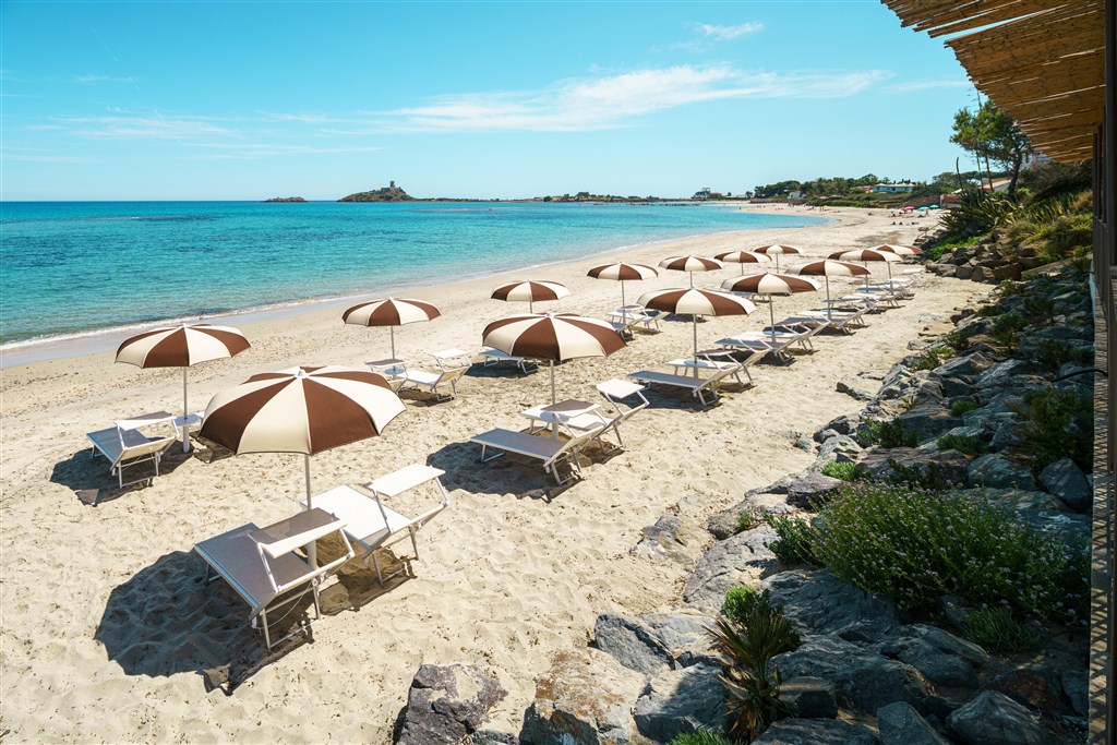 Hotelová pláž s lehátky a slunečníky, Pula, Sardinie