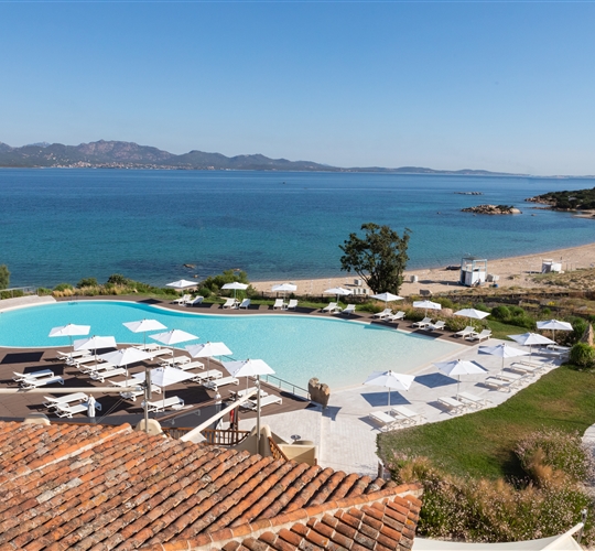 Pohled na bazén a pláž z hotelu, Li Cuncheddi, Sardinie