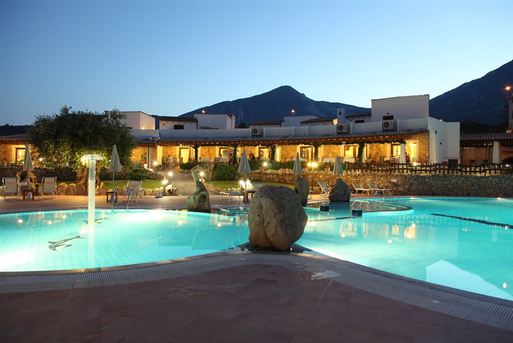 Večerní pohled od bazénu na restauraci a její venkovní terasu, Nuraghe Arvu, Sardinia